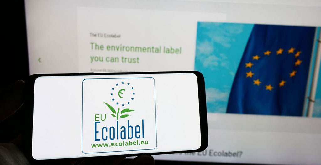 Gros plan sur texture de bois massif brut avec étiquettes de certification environnementale PEFC et NF Environnement, accompagné de feuilles vertes naturelles